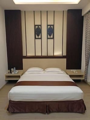 A hotel room with a large bed, bedside tables, and a headboard with vertical panels. - Dawala Hotel (Makassar)