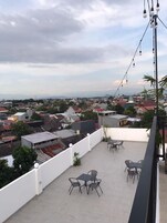 Una terraza en la azotea con mobiliario exterior y vistas a un barrio residencial.