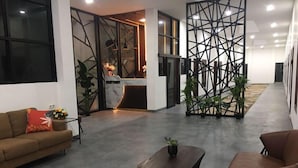 A modern lobby with a sofa, coffee table, and decorative plants. - Dawala Hotel (Makassar)
