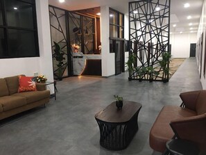 A modern lobby with a sofa, coffee table, and decorative plants. - Dawala Hotel (Makassar)