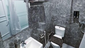 A modern bathroom with a marble wall, a sink, a toilet, and a shower. - Nusa Living Hotel Kediri (Kediri)