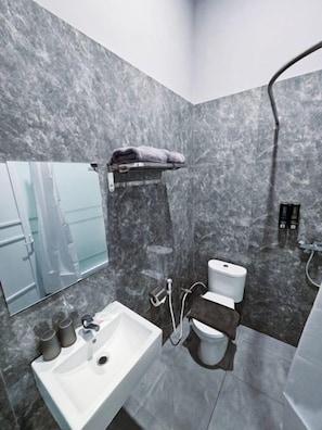 A modern bathroom with a marble wall, a sink, a toilet, and a shower. - Nusa Living Hotel Kediri (Kediri)