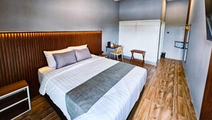 A modern bedroom with a large bed, bedside tables, a desk, and a chair. - Nusa Living Hotel Kediri (Kediri)