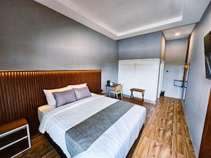 A modern bedroom with a large bed, bedside tables, a desk, and a chair. - Nusa Living Hotel Kediri (Kediri)