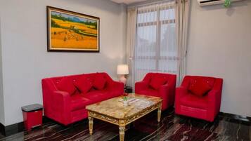 A room with a red sofa set, a marble coffee table, a lamp, and a painting on the wall.