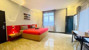A hotel room with a bed, bedside table, lamp, and a view of the outside.
