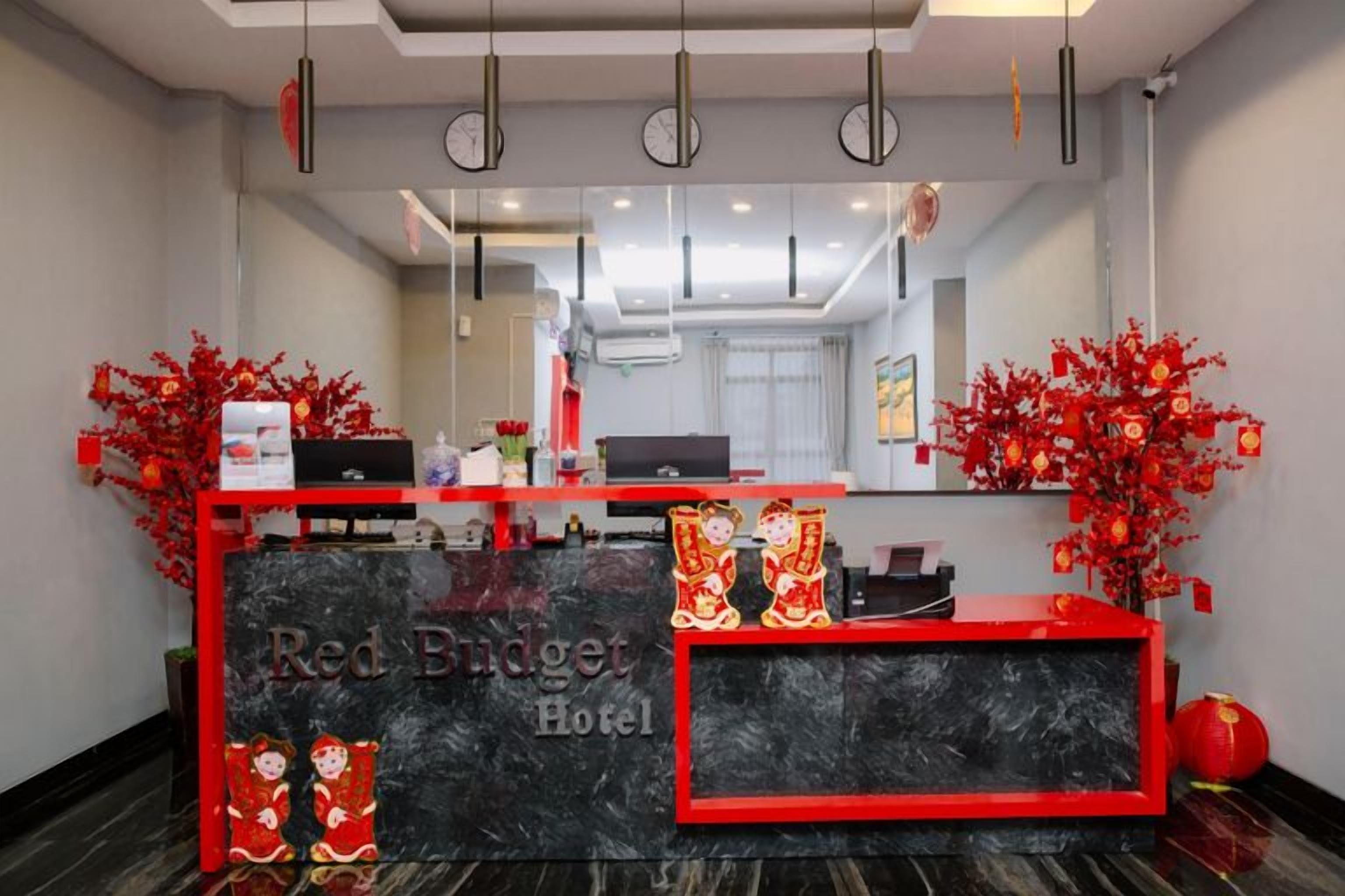 A hotel reception desk with a red and black color scheme, a clock, and a mirror above it.
