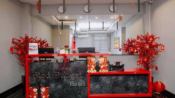 A hotel reception desk with a red and black color scheme, a clock, and a mirror above it.