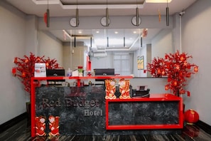 A hotel reception desk with a red and black color scheme, a clock, and a mirror above it. - Red Budget Hotel Ternate (Ternate)