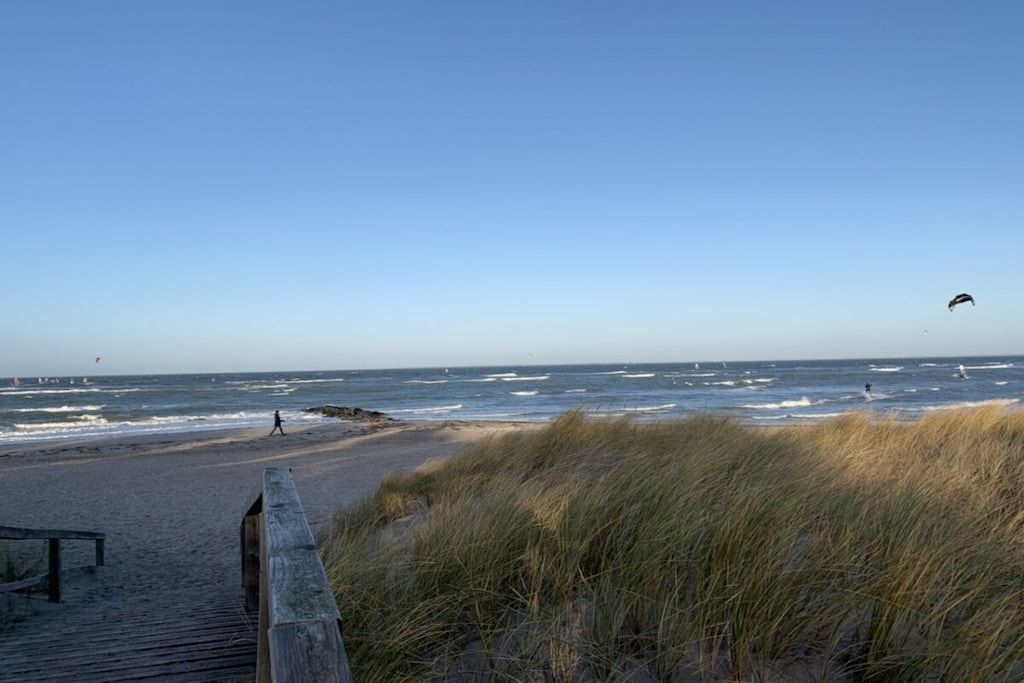 Une plage avec une promenade en bois et des dunes.