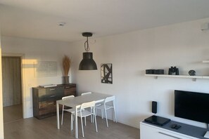 A modern living room with a dining area, a flat-screen TV, and a fireplace. - Sunset 72 - House Berlin (Großenbrode)