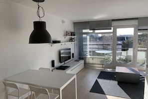 A modern kitchen with a dining area, a large window, and a balcony with a table and chairs. - Sunset 72 - House Berlin (Großenbrode)