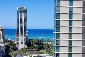A high-rise hotel with multiple floors, overlooking a coastal area with clear blue waters and boats. - Luxury Waikiki 1BR: Ocean View & Free Parking (Honolulu)