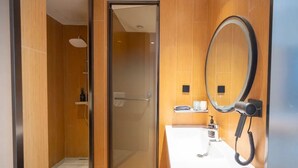 A modern bathroom with a glass shower door, a white sink, a mirror, and a hairdryer mounted on the wall. - Hongguo Hotel (Xiangyang)