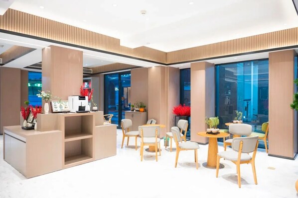 A modern hotel lobby with a reception desk, seating area, and large windows. - Hongguo Hotel (Xiangyang)