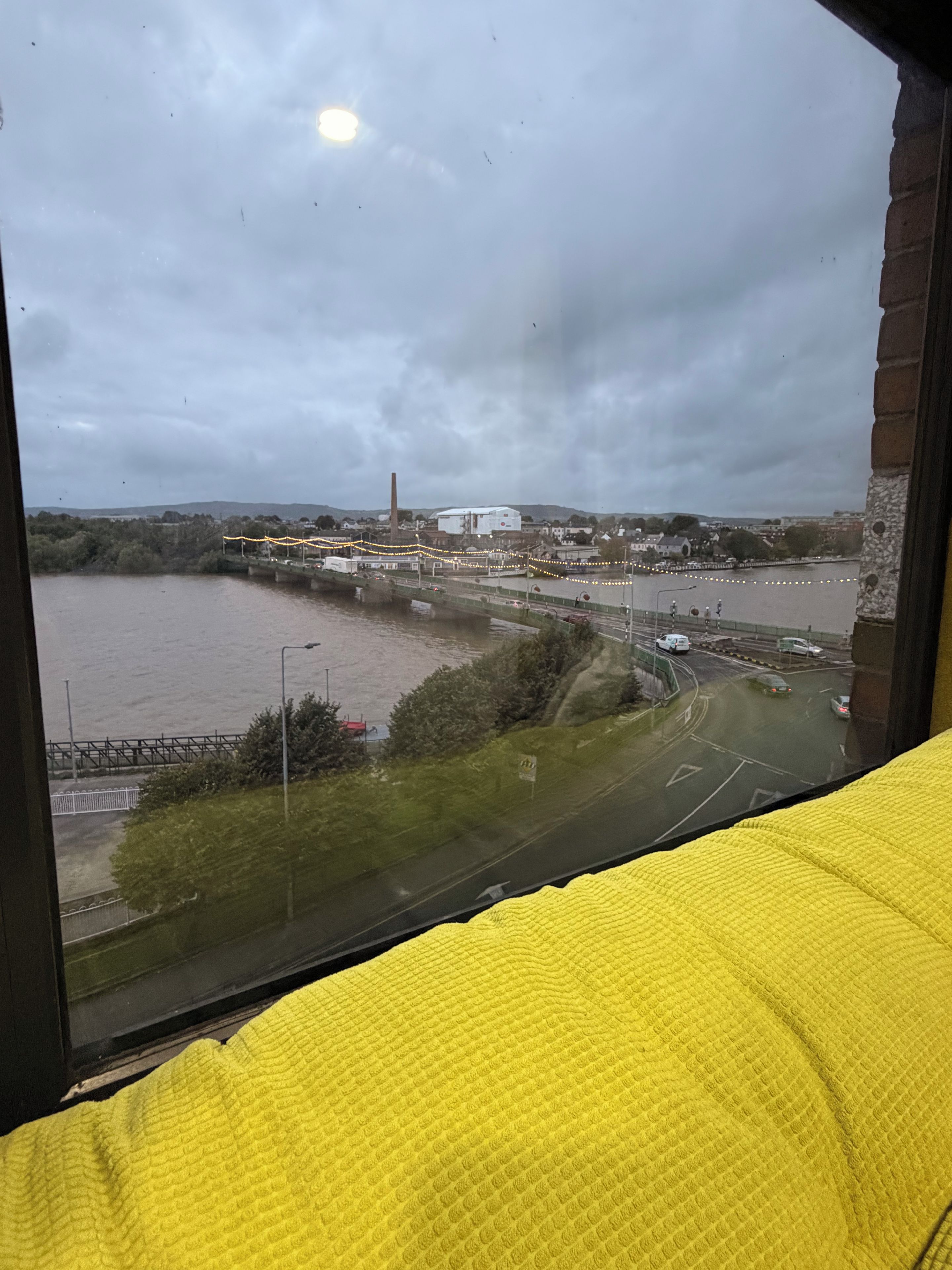 Vista de un río con un puente, un edificio y una carretera con vehículos.