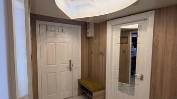 A hallway with a marble floor, a bench, a wooden wall, and a door with a mirror.