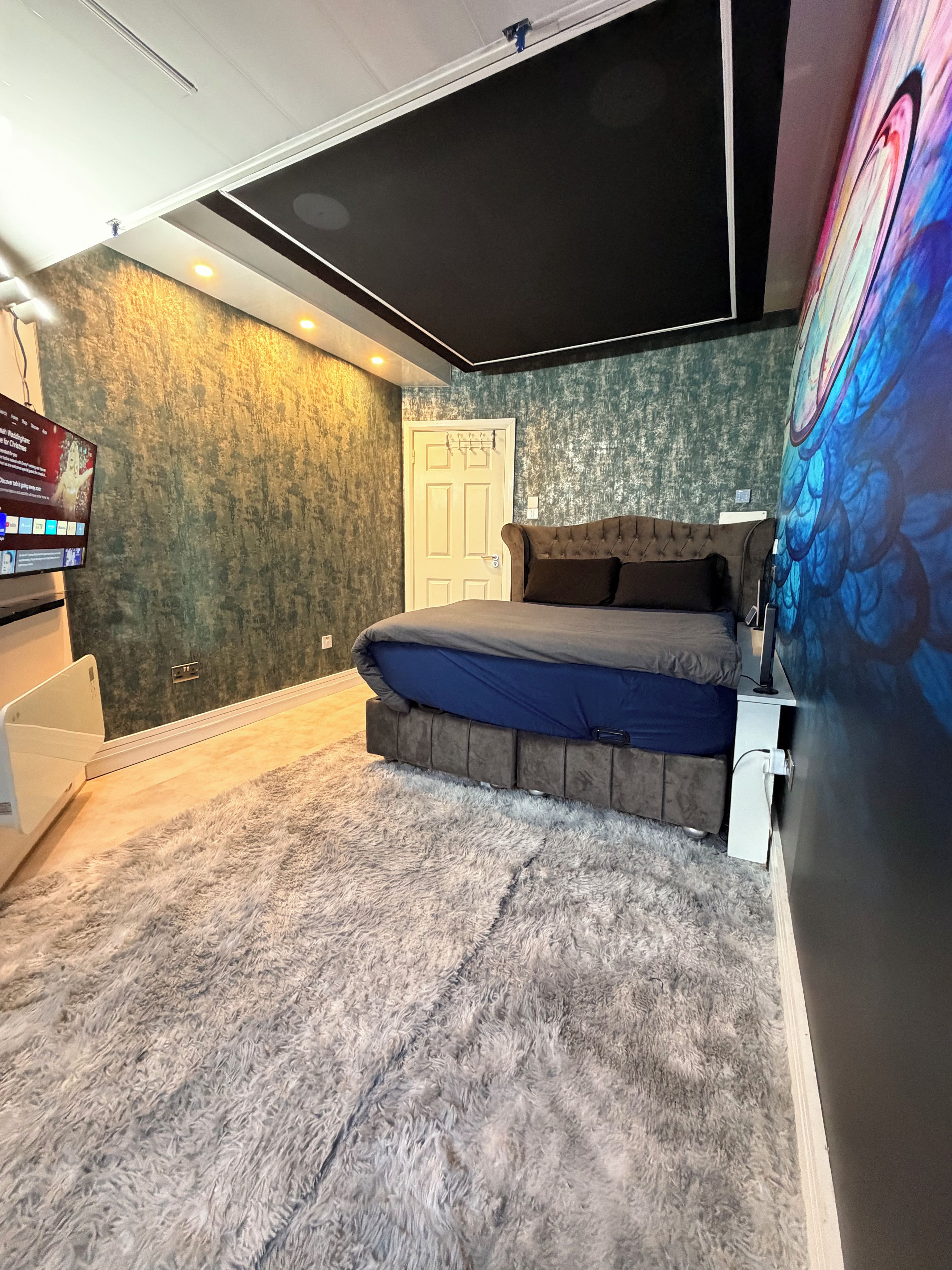 Ein Schlafzimmer mit einem Bett, einem Fernseher und einer Tür.