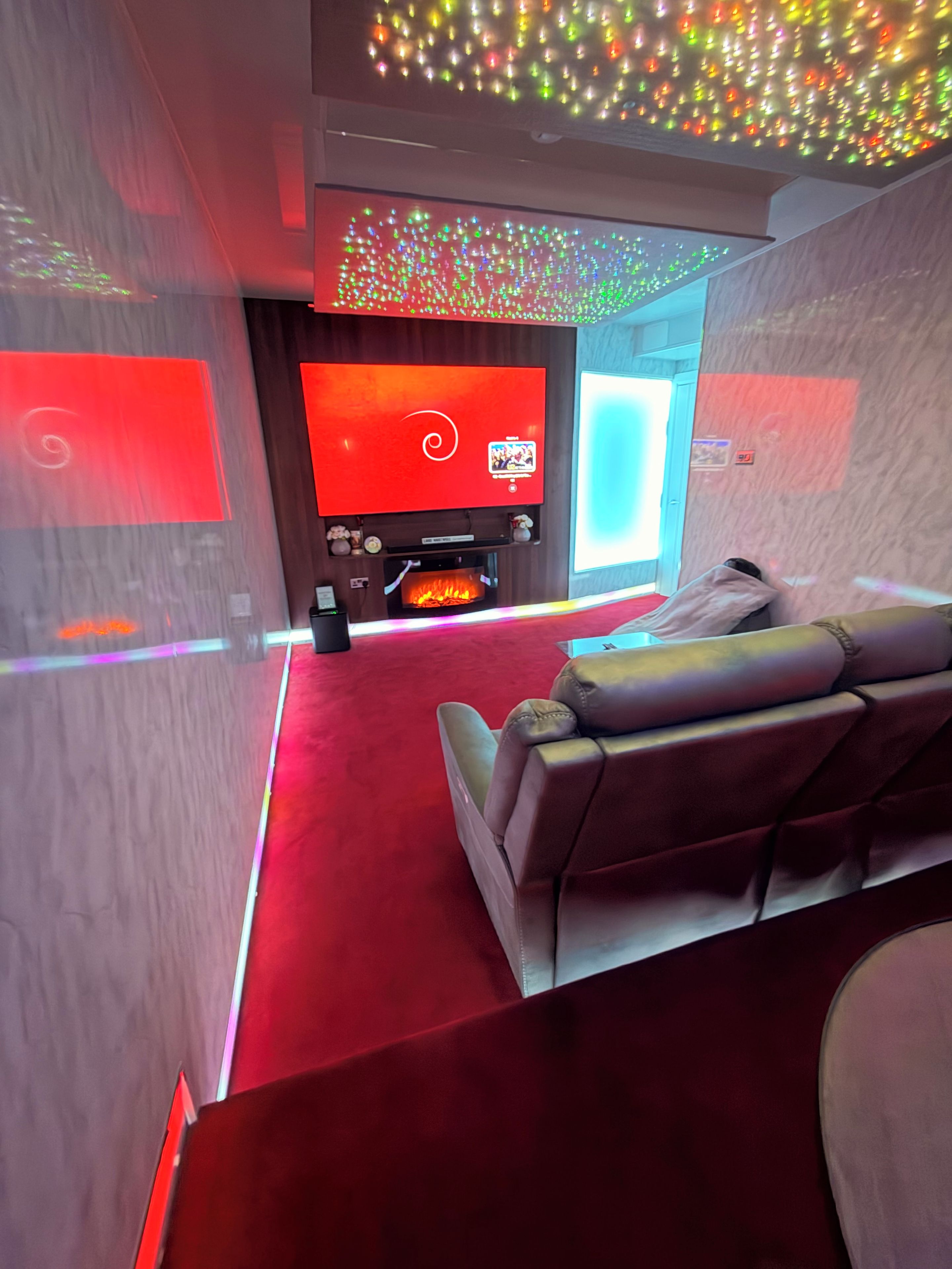 Un salon moderne avec une moquette rouge, un canapé en cuir et un téléviseur à écran plat.