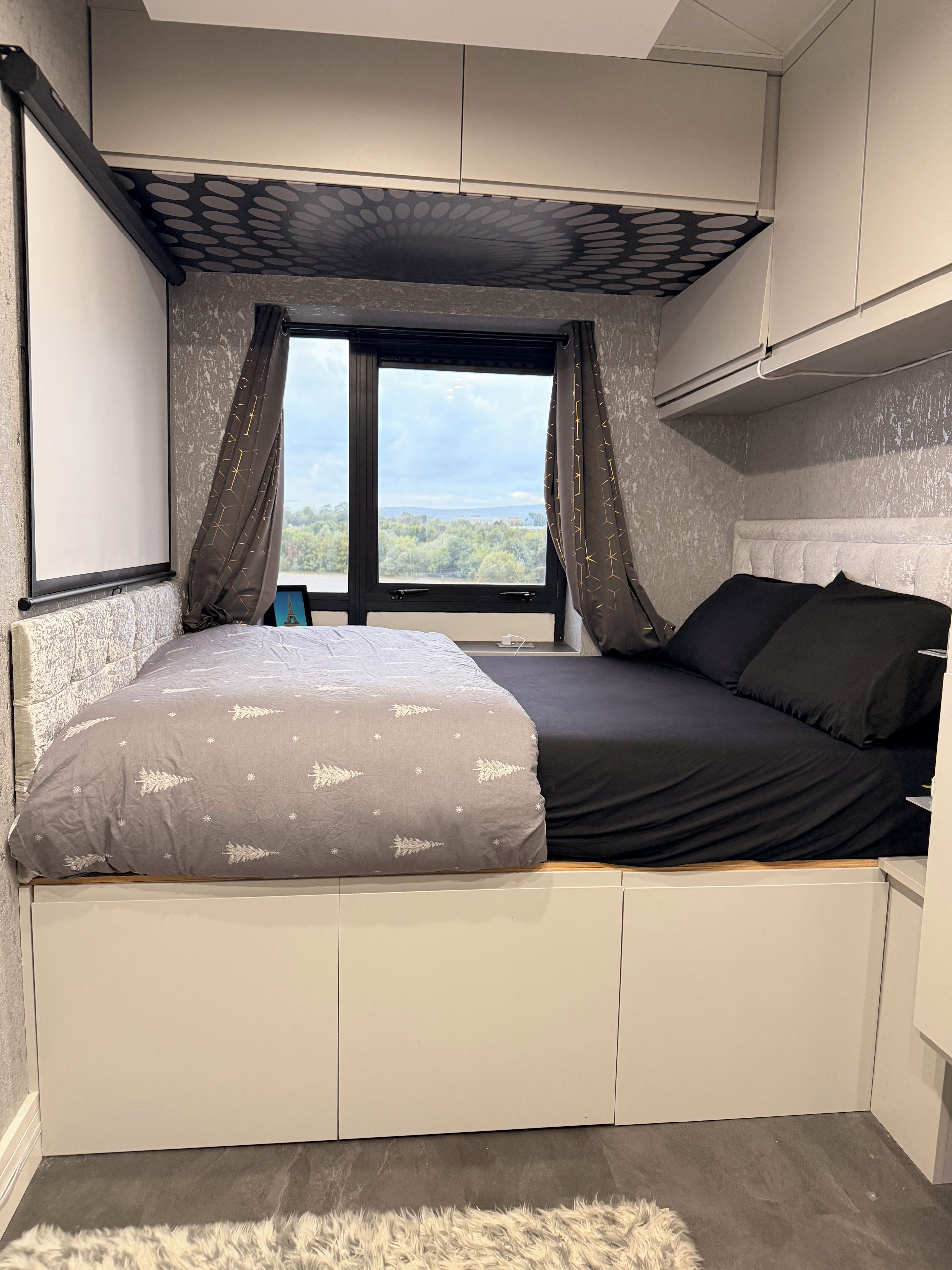 Ein Schlafzimmer mit einem Bett, einem Fenster und Blick ins Freie.