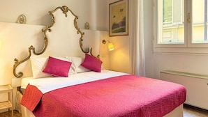 Un lit avec une tête de lit décorée, une literie blanche et une couverture rouge.