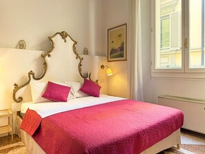 Un letto con una testiera decorata, biancheria da letto bianca e una coperta rossa.