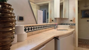 Une salle de bain équipée d’un lavabo, d’un miroir et d’un porte-rouleau de papier toilette.