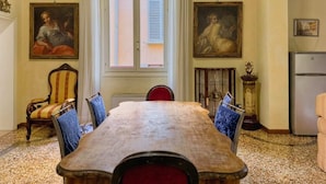 Une salle à manger avec une grande table en bois, des chaises et deux tableaux accrochés aux murs.