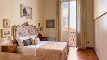 Una camera d'albergo con un letto, un comodino, una lampada e vista sull'esterno attraverso una finestra.