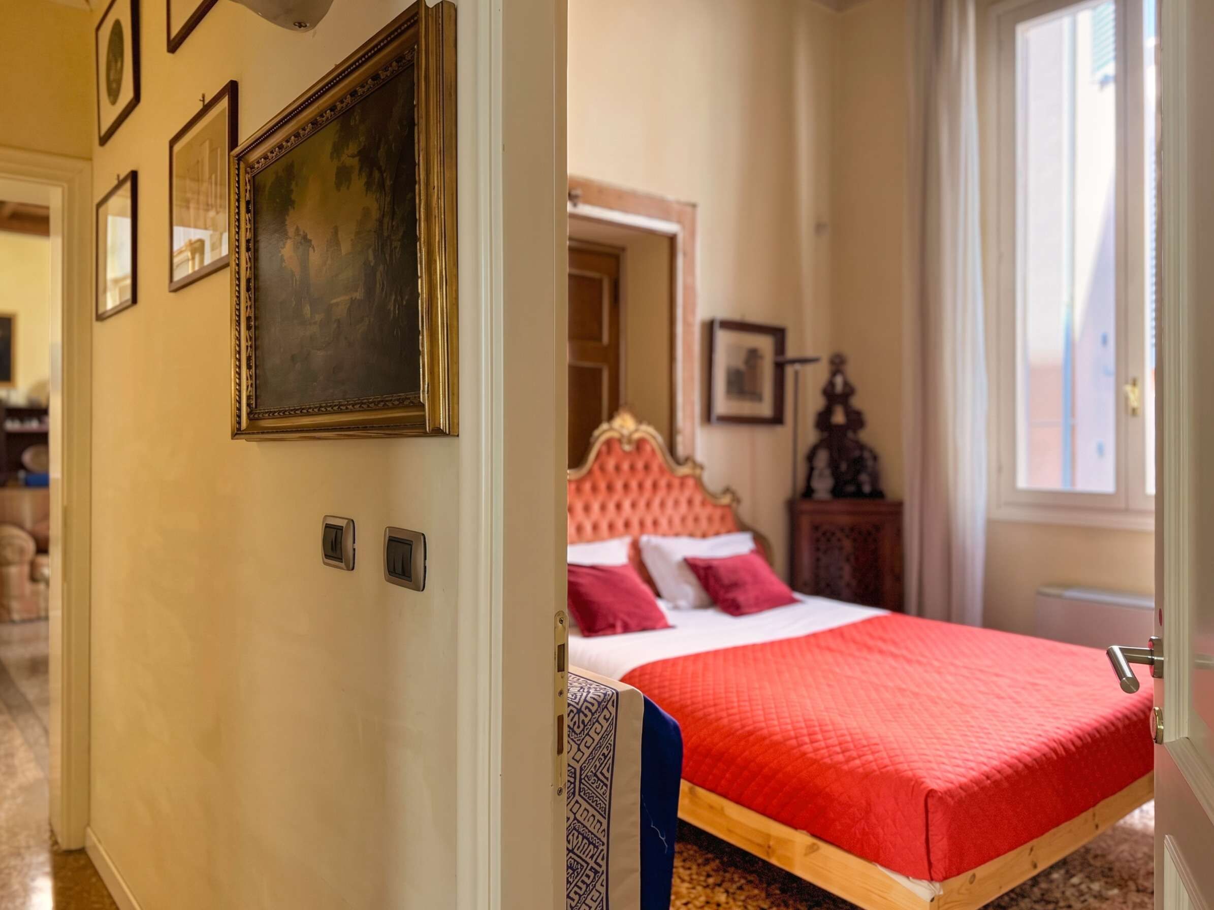 Ein Hotelzimmer mit einem Bett, einer Tür und einem Flur mit gerahmten Bildern.