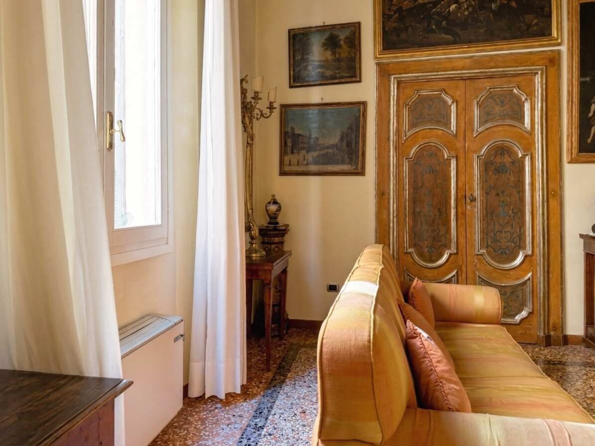 Ein Zimmer mit einer Couch, einer Holztür und einem Fenster mit Vorhängen.