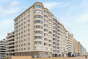 Ein mehrstöckiges Hotel mit einer gebogenen Fassade, zahlreichen Balkonen und einem Eingang im Erdgeschoss.