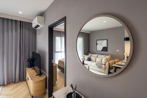 A modern living room with a round mirror reflecting the interior, a sofa, a coffee table, and a television on a wooden stand. - Bang Tao - Spacious Private Balcony (Tambon Choeng Thale)