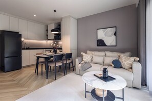 A modern kitchen with a dining area, a sofa, and a coffee table. - Bang Tao - Spacious Private Balcony (Tambon Choeng Thale)