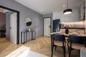 A modern kitchen with a dining area, featuring a round mirror, a black-framed table, and a hanging light fixture. - Bang Tao - Spacious Private Balcony (Tambon Choeng Thale)