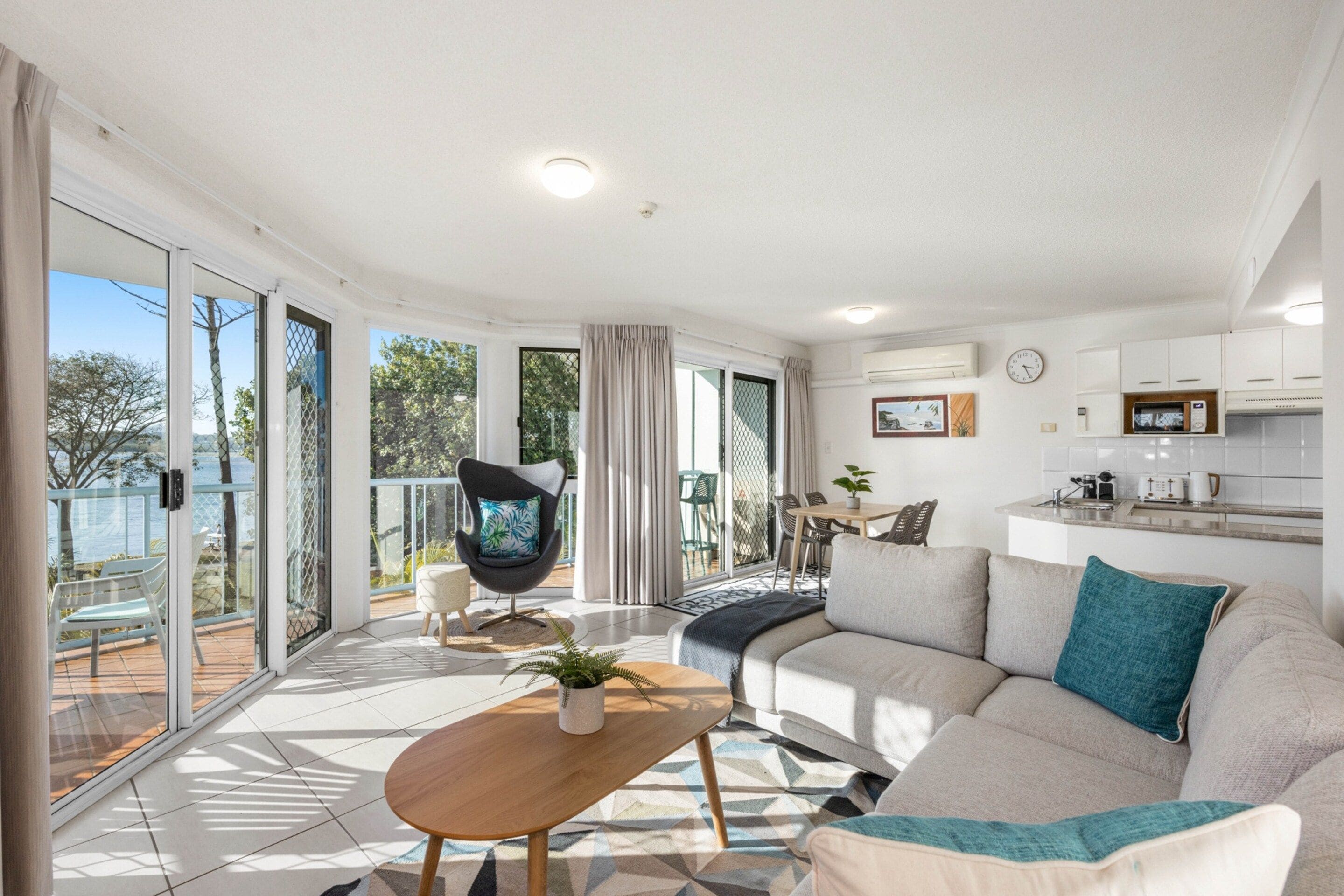A modern living room with a sofa, a coffee table, and a dining area with chairs.