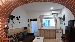 En kompakt bolig med tekøkken, spiseplads og opholdsområde med sofa og bord.