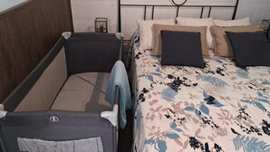En dobbeltseng med blomstret sengetæppe, to puder, et natbord og et sengebord med lampe.