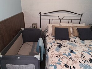 A double bed with a floral bedspread, two pillows, a nightstand, and a bedside table with a lamp. - Fully furnished apartment next to the subway, near the beach (València)