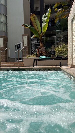 A swimming pool with a bench and a sign indicating spa rules and hours. - Luxe & Modern 1-bed with panel living space w Pool, Hot tub, Gym -Marina del Rey (Marina del Rey)