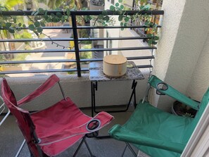 A balcony with two folding chairs, a small table with a wooden object, and a potted plant. - Luxe & Modern 1-bed with panel living space w Pool, Hot tub, Gym -Marina del Rey (Marina del Rey)