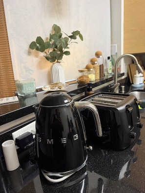 Uma cozinha com cafeteira preta, torradeira e pia.