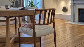 Una mesa de madera con sillas, una chimenea y una planta de fondo.