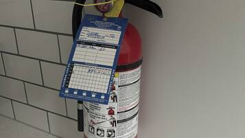 A fire extinguisher mounted on a wall with a label and a pressure gauge.