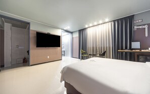 A modern hotel room with a large bed, a flat-screen TV, a desk with a computer, and a chair. - Aria Business Hotel (Pohang)
