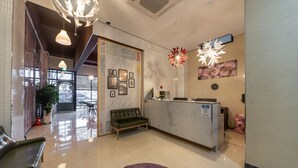 Uma área de recepção de hotel com balcão, um sofá verde e um tapete roxo.