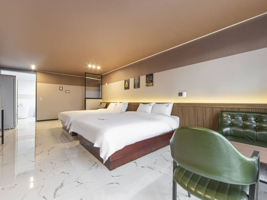 Una habitación de hotel con una cama grande, una silla verde, una mesita y vistas al mar.