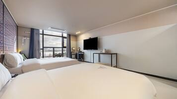 Quarto de hotel com uma cama grande, televisão, escrivaninha e vista da cidade.