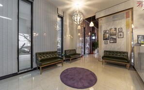 A modern lobby with leather sofas, a purple rug, and a large chandelier. - Aria Business Hotel (Pohang)