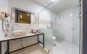 Een moderne badkamer met een douche met glazen wand, een wit wastafelmeubel en een spiegel erboven.